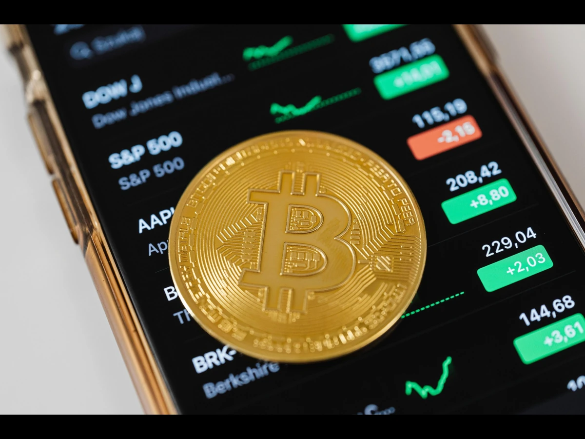 Pièce de Bitcoin sur un téléphone avec des cours de bourse